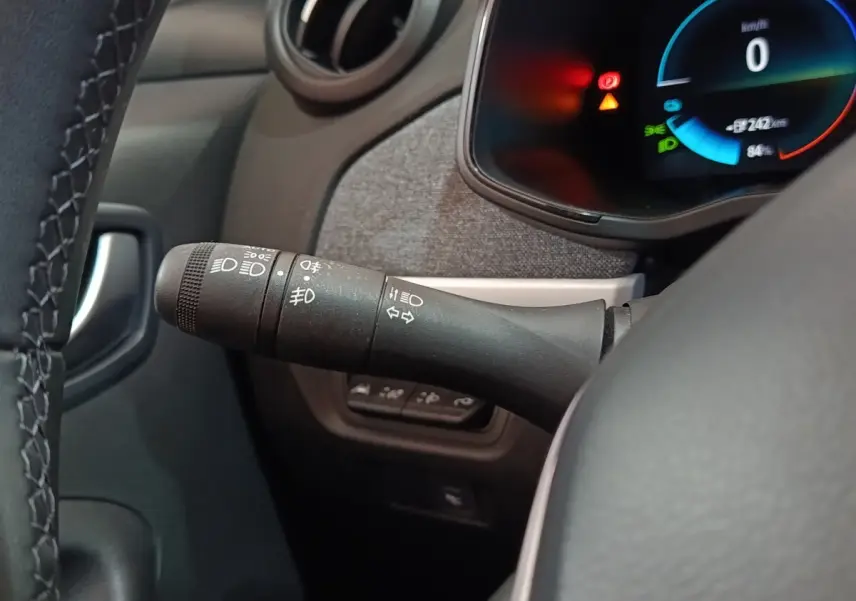 Gros plan sur la manette de commande des phares et clignotants côté gauche du tableau de bord de la Renault ZOE blanche.