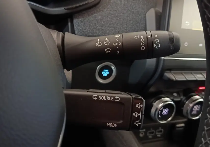 Gros plan sur les commandes au volant et bouton démarrage d’une Renault ZOE blanche, intérieur moderne et fonctionnel.