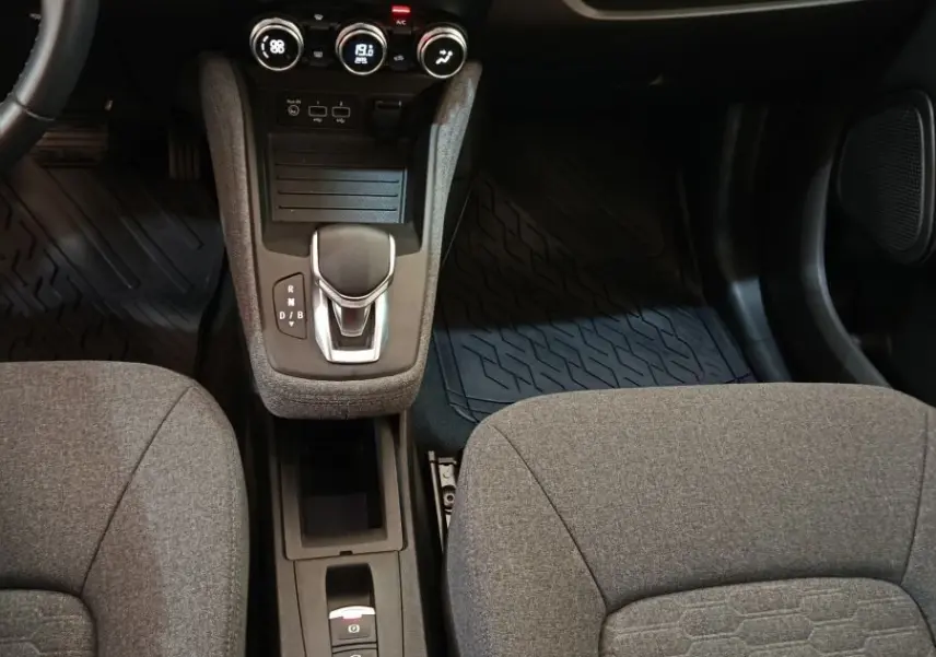 Vue intérieure centrée sur la console centrale et les sièges gris de la Renault ZOE électrique blanche, avec écran tactile et levier de vitesses.