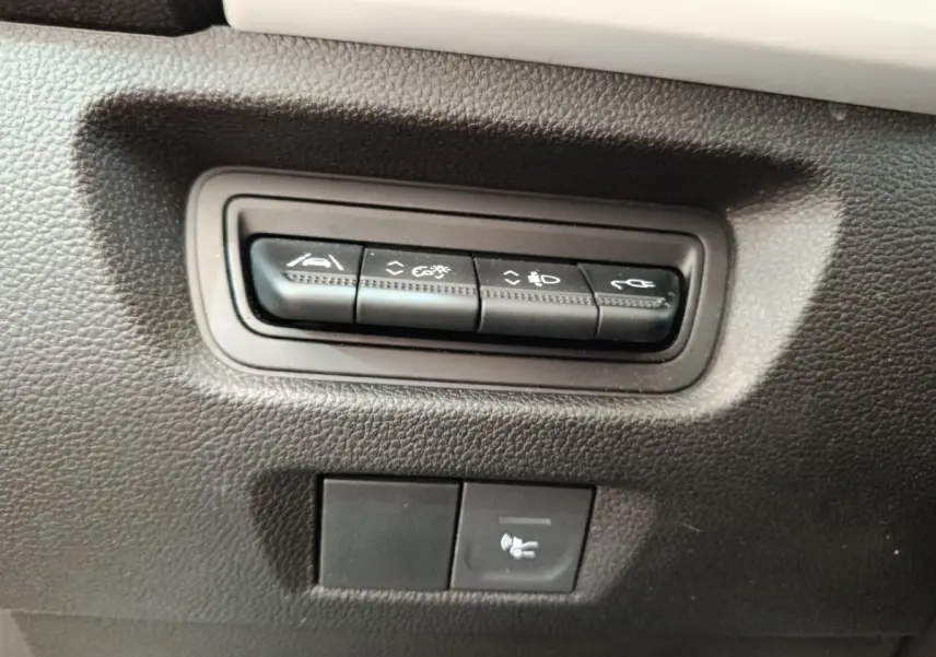 Gros plan sur les boutons de commande noirs intégrés dans le tableau de bord noir d'une Renault ZOE blanche.