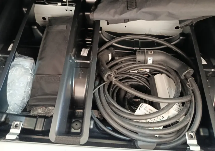 Coffre ouvert vu de dessus de la Renault ZOE blanche 2023 montrant le câble de charge électrique rangé.