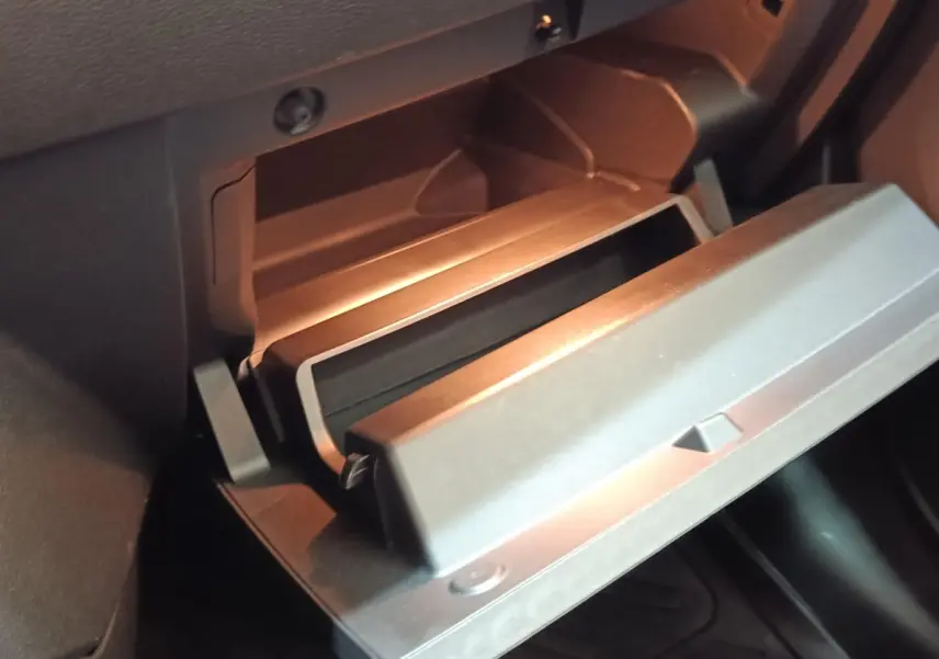 Gros plan sur la boîte à gants ouverte de la Renault ZOE blanche, intérieur noir avec éclairage doux.