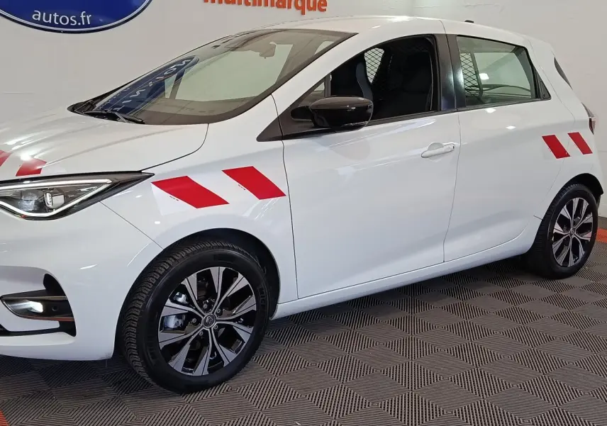 Vue de profil droit d'une Renault ZOE blanche 2023 avec bandes rouges diagonales sur ailes avant et arrière.