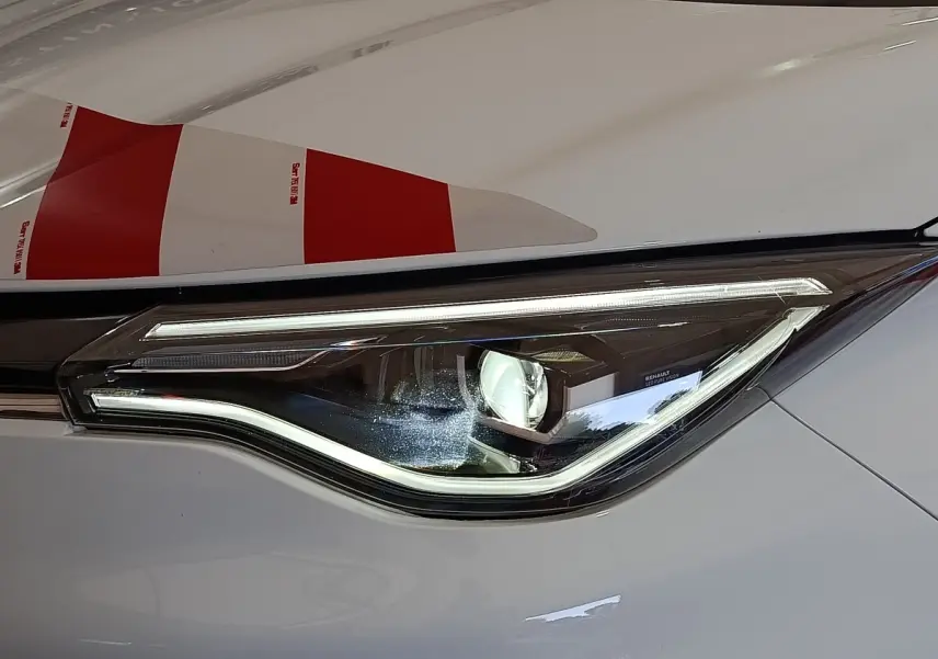 Gros plan sur le phare avant droit LED de la Renault ZOE blanche, soulignant son design moderne et épuré.
