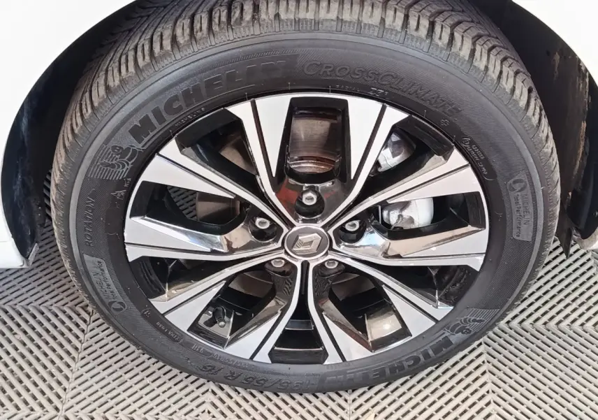 Gros plan sur la roue avant droite d'une Renault ZOE blanche, jante alliage bicolore et pneu Michelin.