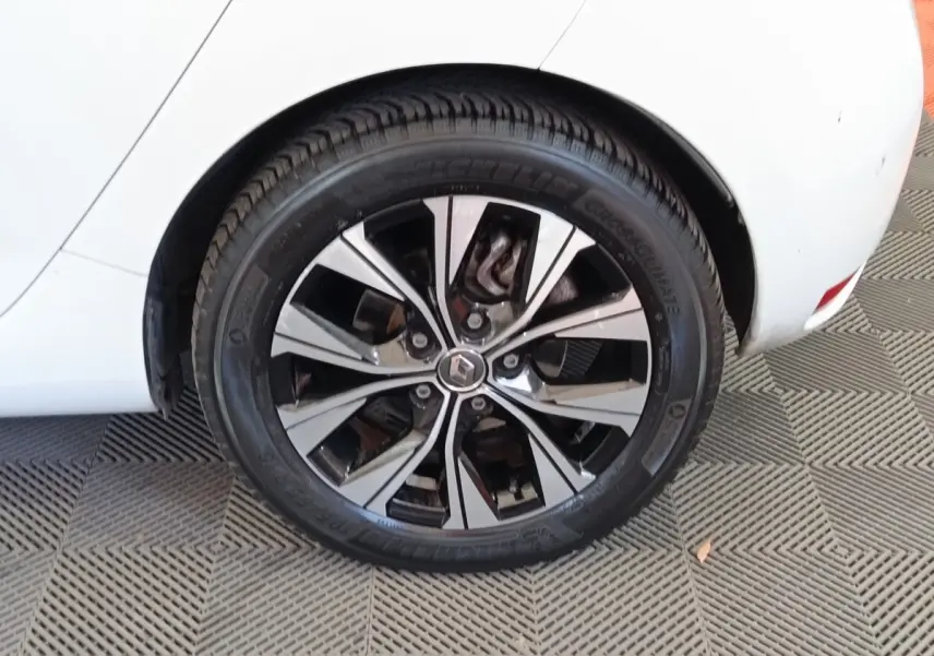 Gros plan sur la roue arrière droite de la Renault ZOE blanche avec jante alliage bicolore et logo Renault central.