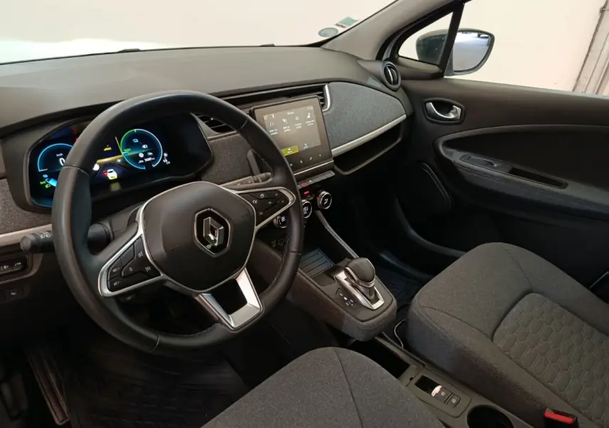 Vue intérieure côté conducteur de la Renault ZOE blanche 2023, volant cuir multifonctions et écran tactile central.