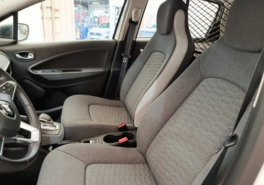 Vue intérieure côté conducteur de la Renault ZOE blanche 2023, sièges gris avec détails clairs et volant multifonctions.