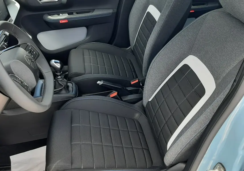 Vue intérieure côté conducteur de la Citroën C3 Turbo 100ch Plus 2026, sièges tissu noir et gris, volant et levier de vitesse visibles.
