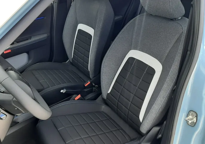 Vue intérieure côté conducteur de la Citroën C3 Turbo 100ch Plus 2026 avec sièges tissu noir et gris, portière bleu Monte Carlo ouverte.