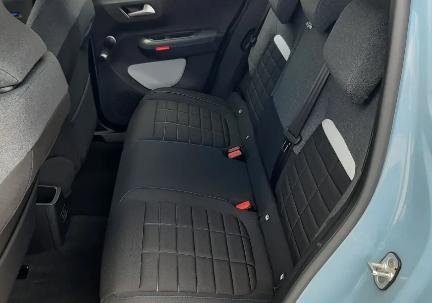 Vue intérieure arrière côté droit de la Citroën C3 2026, sièges tissu noir avec surpiqûres bleues et portière bleu Monte Carlo.