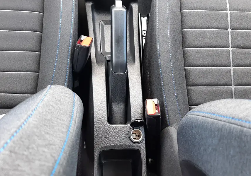 Vue plongeante sur la console centrale et les sièges avant en tissu gris avec surpiqûres bleues d'une Citroën C3 Turbo 100ch Plus 2026.