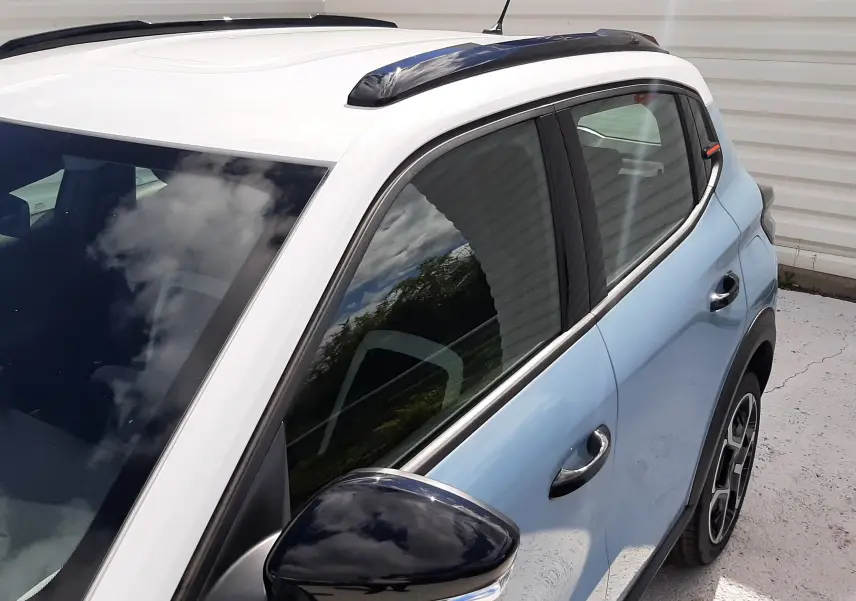 Vue 3/4 arrière côté droit d'une Citroën C3 Turbo 100ch Plus bleu Monte Carlo avec toit blanc et rétroviseur noir brillant.