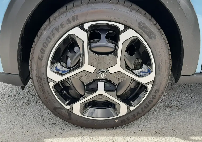 Gros plan sur la roue avant gauche d'une Citroën C3 bleu Monte Carlo avec jante noire et argentée au design moderne.