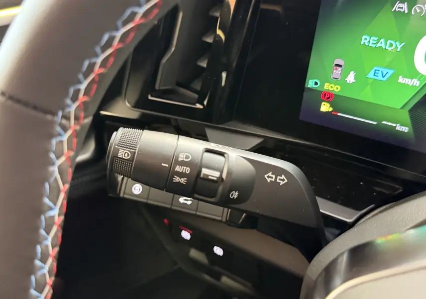 Gros plan sur la commande des feux et clignotants à gauche du volant avec surpiqûres tricolores du volant du Renault Austral E-Tech 2026.