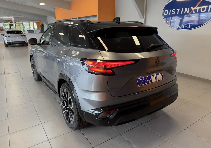 Vue 3/4 arrière du Renault Austral E-Tech gris schiste avec toit noir et jantes alliage noires en showroom.