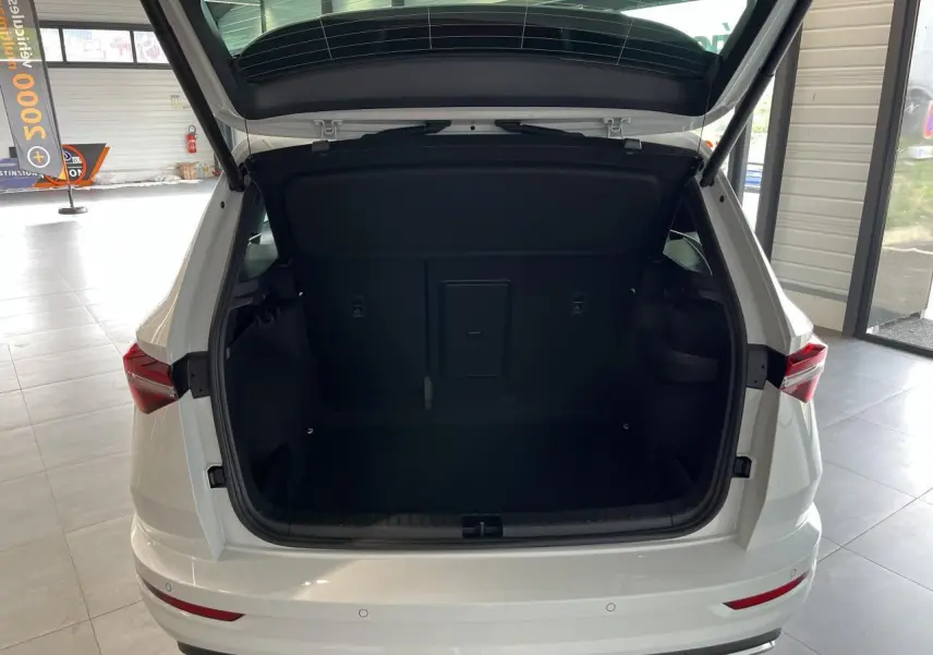 Coffre ouvert vu de l'arrière d'un SUV SKODA KAROQ blanc 2025 avec hayon électrique et feux arrière LED.