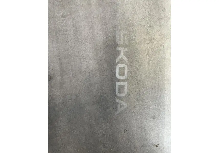 Projection lumineuse du logo SKODA au sol, visible sous un véhicule blanc SKODA KAROQ Sportline 2025.