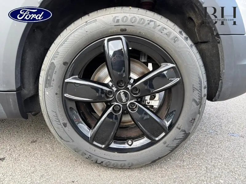 Gros plan sur la roue avant droite d'une MINI Countryman Melting Silver III avec jante noire brillante cinq branches.