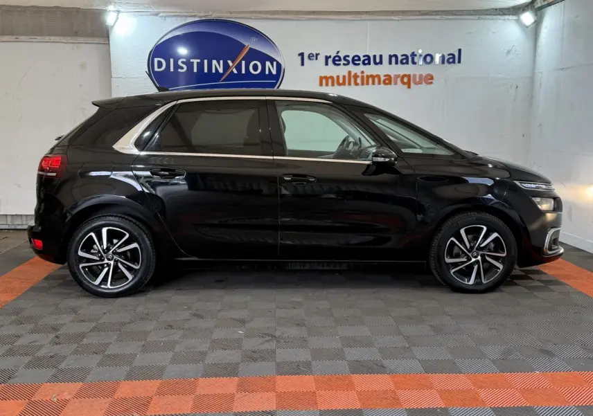 Profil droit d'une Citroën C4 Spacetourer noire 2020 avec jantes alliage et vitres teintées en intérieur showroom.