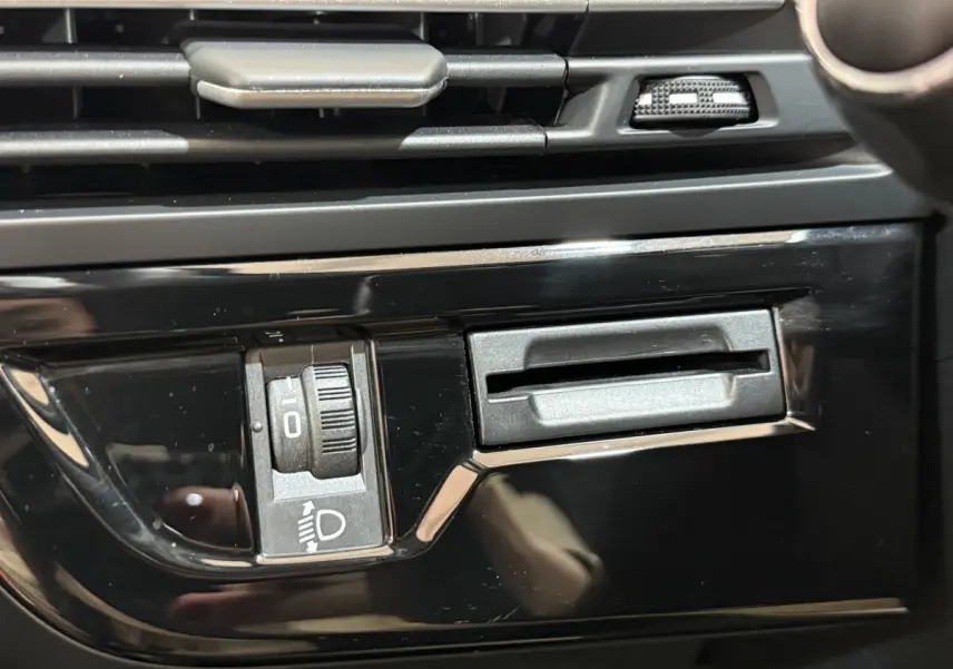 Gros plan sur la commande de réglage des phares et la fente de carte dans l’habitacle noir du Citroën C4 Spacetourer 2020.