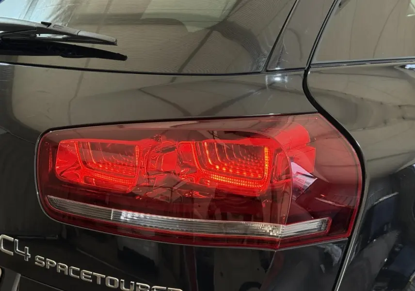 Gros plan sur le feu arrière droit rouge et le logo C4 Spacetourer sur la carrosserie noire brillante.