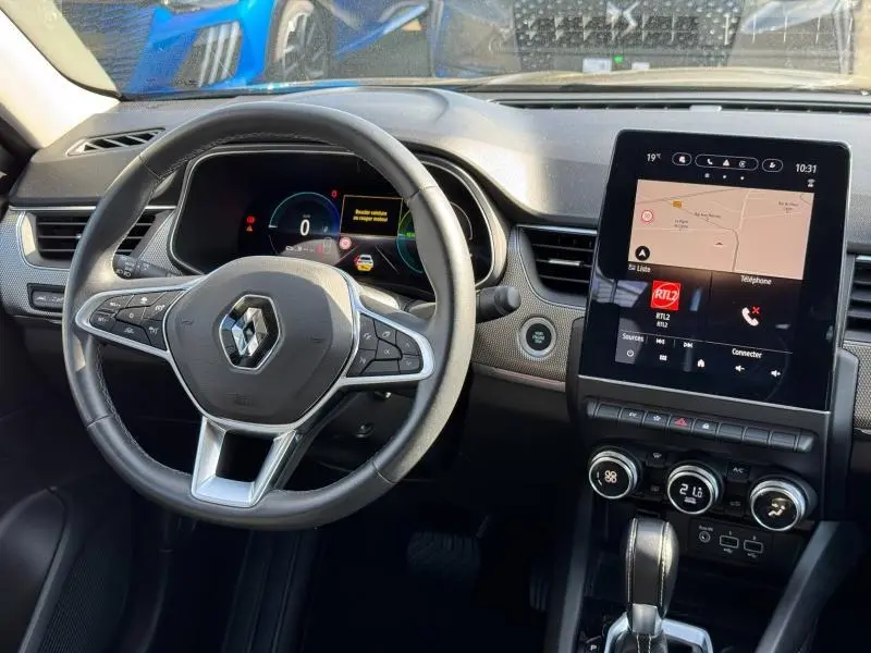 Vue intérieure du tableau de bord et volant noir multifonction du Renault Arkana 1.6 E-Tech 145ch hybride, avec écran tactile central.