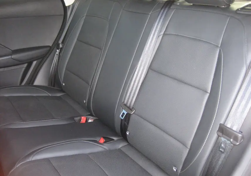 Vue rapprochée des sièges arrière en cuir noir du MG ZS 1.5 HYBRID+197 LUXURY, avec ceintures de sécurité visibles.