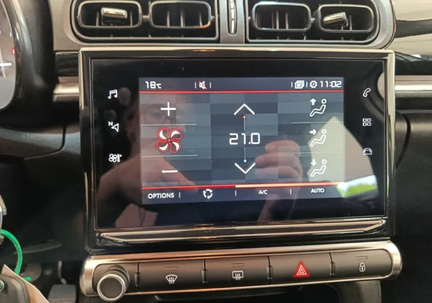 Écran tactile central affichant la climatisation à 21°C dans l'habitacle noir de la Citroën C3 blanche.