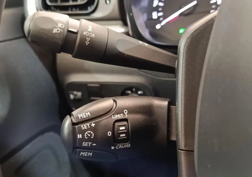 Gros plan sur la commande de régulateur de vitesse côté gauche du volant d'une Citroën C3 blanche 2022.