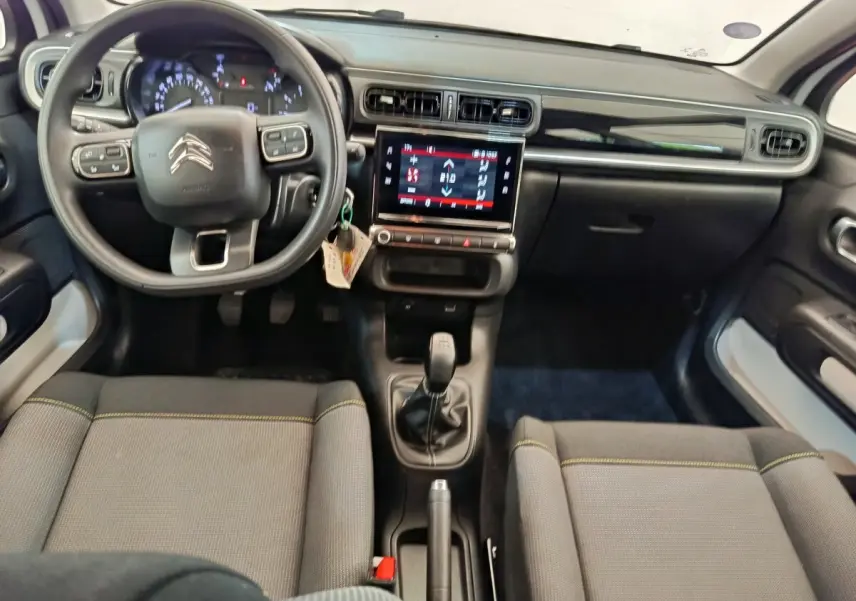 Vue intérieure avant de la Citroën C3 blanche 2022, volant multifonctions, écran tactile central et boîte manuelle.