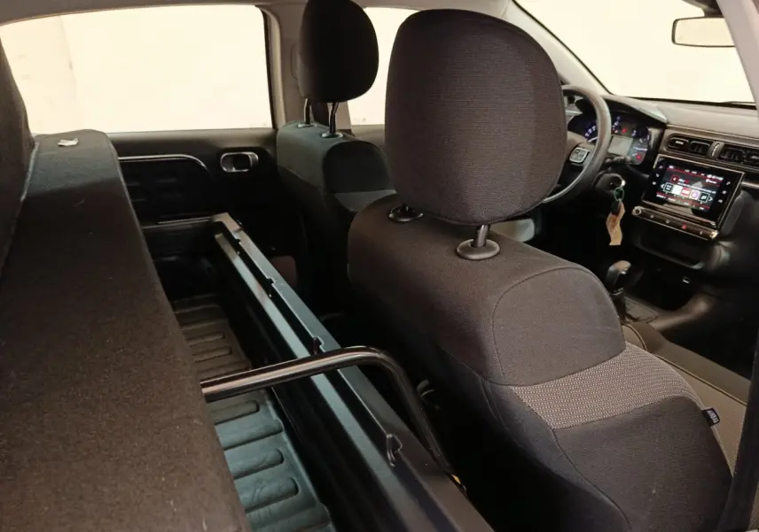Vue intérieure arrière droite de la Citroën C3 blanche 2022, montrant les sièges noirs et l'écran tactile du tableau de bord.