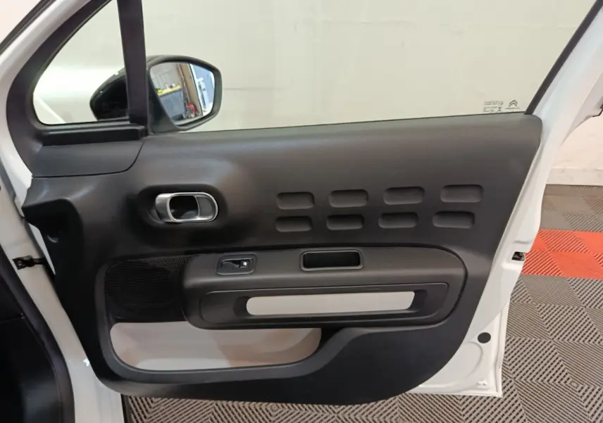 Vue intérieure de la porte avant gauche blanche d'une Citroën C3 avec poignée argentée et haut-parleur intégré.