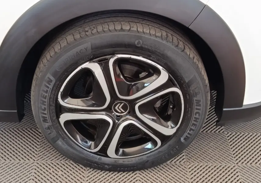 Gros plan sur la roue avant droite d'une Citroën C3 blanche, avec jante alliage noire et argentée au design moderne.