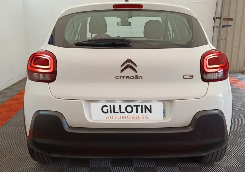 Vue arrière d'une Citroën C3 blanche avec feux arrière LED et pare-chocs noir dans un garage.