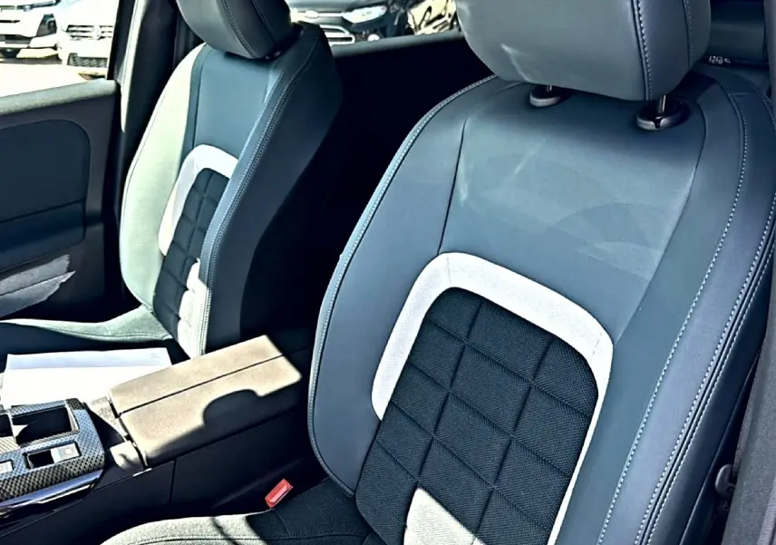 Vue rapprochée des sièges avant gris et noirs avec accoudoir central dans un Citroën C5 Aircross hybride 2026.
