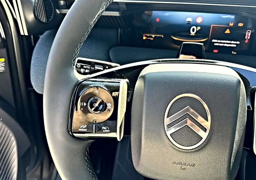 Gros plan sur le volant multifonction noir du Citroën C5 Aircross 2026 avec logo chrome et tableau de bord numérique en arrière-plan.