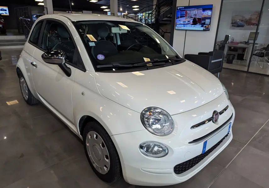 Vue 3/4 avant droite d'une Fiat 500 blanche Bossanova exposée en showroom avec jantes acier et rétroviseurs noirs.