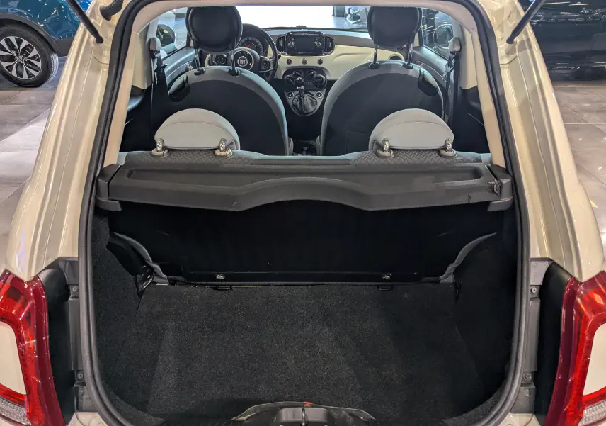 Coffre ouvert d'une FIAT 500 Blanc Bossanova vue de l'arrière, avec intérieur noir et tableau de bord visible.
