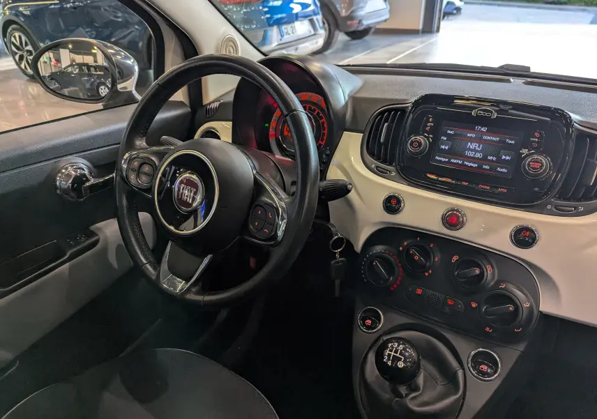 Vue intérieure côté conducteur du tableau de bord blanc Bossanova et volant noir de la Fiat 500 1.2 69 CH Popstar 2018.