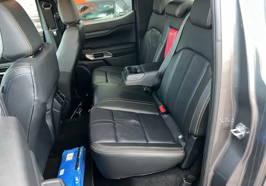 Vue intérieure côté droit des sièges arrière en cuir noir avec surpiqûres jaunes du Ford Ranger gris carbone 2025 Wildtrak Plus.