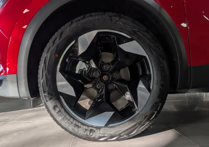 Gros plan sur la roue avant gauche du Renault Captur rouge Flamme avec jante noire et argentée au design géométrique.