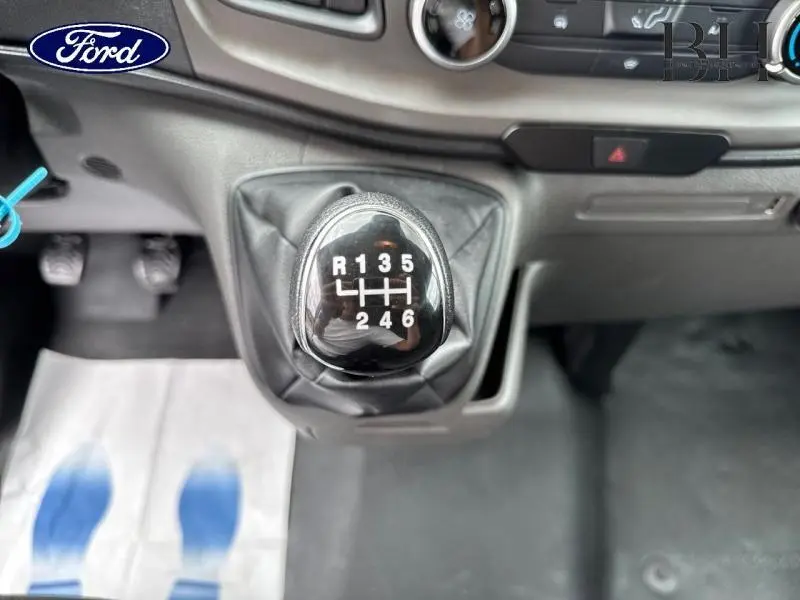 Le levier de vitesses manuel noir du Ford Transit Custom blanc, vue rapprochée de l'intérieur avec tableau de bord gris.