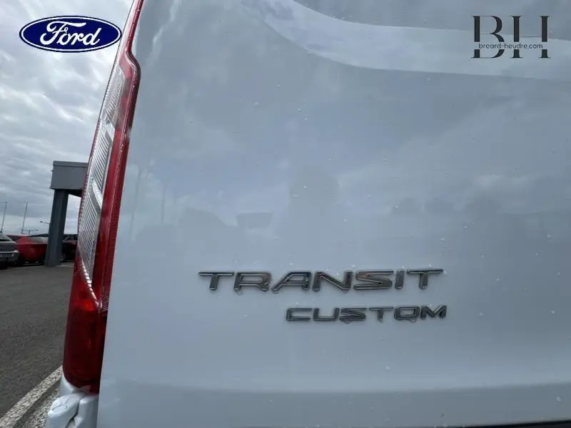 Gros plan sur l'arrière blanc glacier du Ford Transit Custom avec logo et feu arrière gauche visible