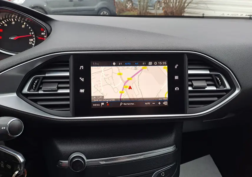Vue rapprochée de l'écran tactile central avec navigation GPS du tableau de bord noir d'une Peugeot 308 gris 2019.