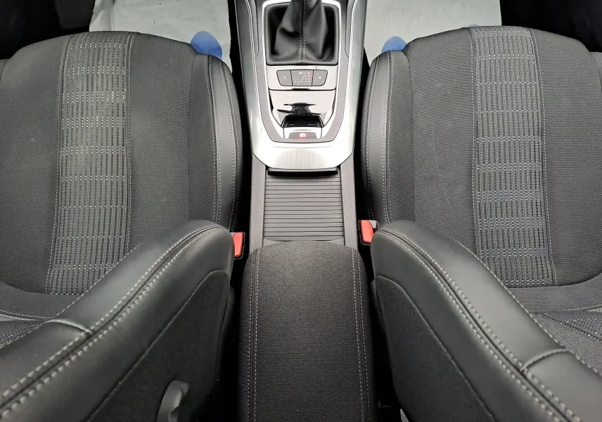 Vue plongeante sur les sièges avant noirs et la console centrale avec levier de vitesse d'une Peugeot 308 gris 2019.