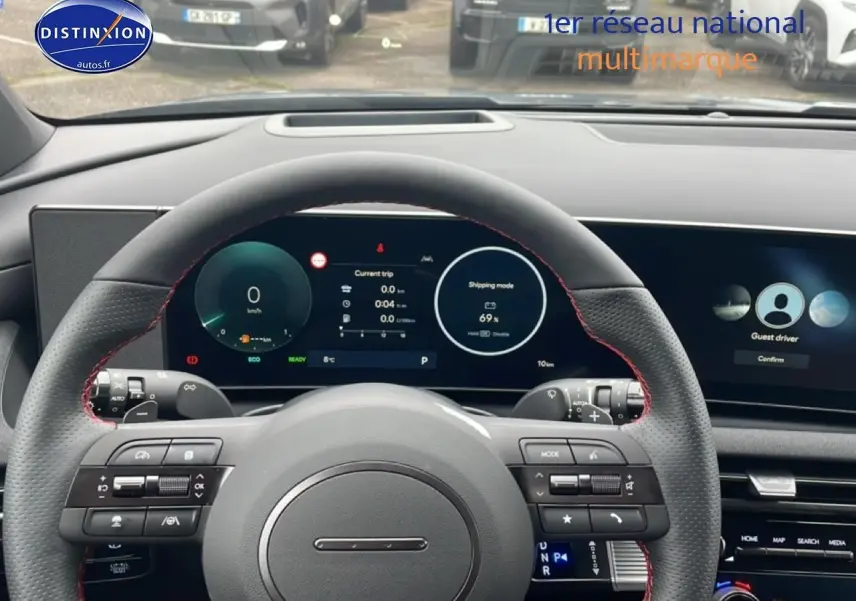 Vue intérieure centrée sur le volant cuir noir N Line avec surpiqûres rouges et tableau de bord digital du Hyundai Tucson gris.