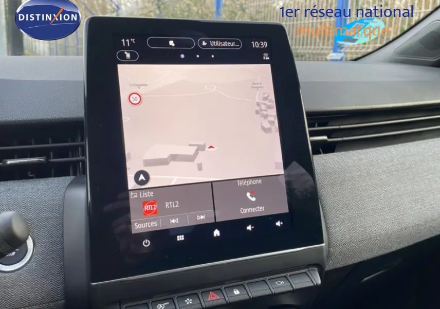 Vue rapprochée de l’écran tactile central du tableau de bord de la Renault Clio 2025 avec interface de navigation et radio.