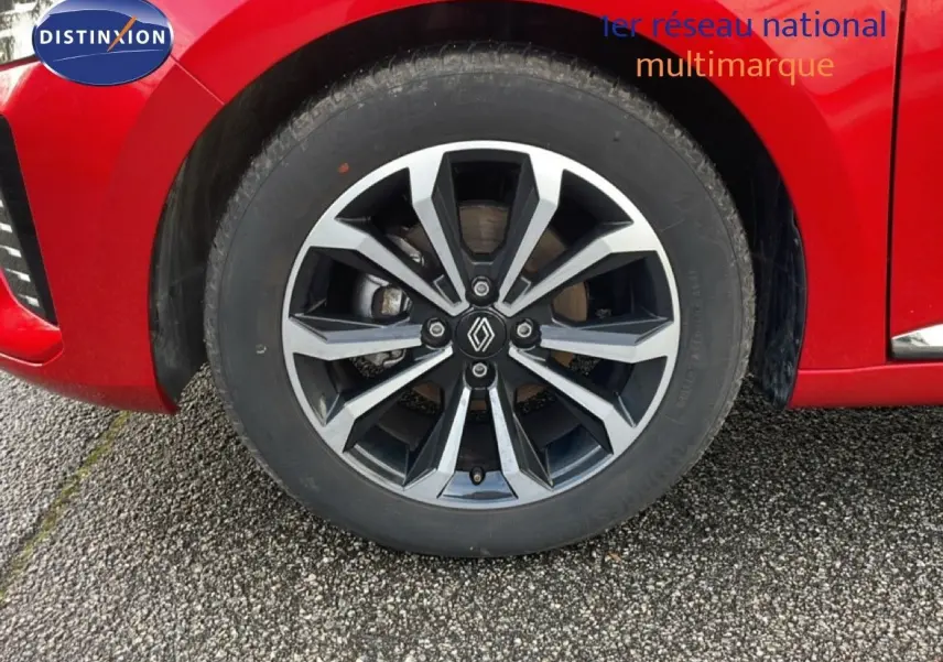 Gros plan sur la roue avant droite d'une Renault Clio rouge Désir Métal avec jante alliage au design moderne.