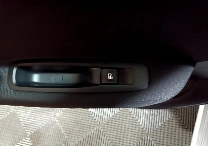 Gros plan sur la commande de lève-vitre noir intégrée à la porte intérieure d’une Renault Mégane Business Blue dCi 115 EDC gris clair.
